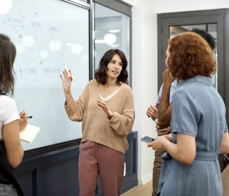 Colleagues talking beside a dry erase board