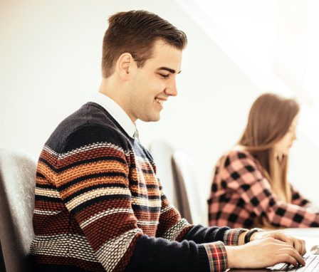 Male student smiling while working on laptop