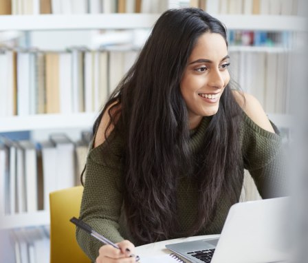 Woman student working on laptop in library